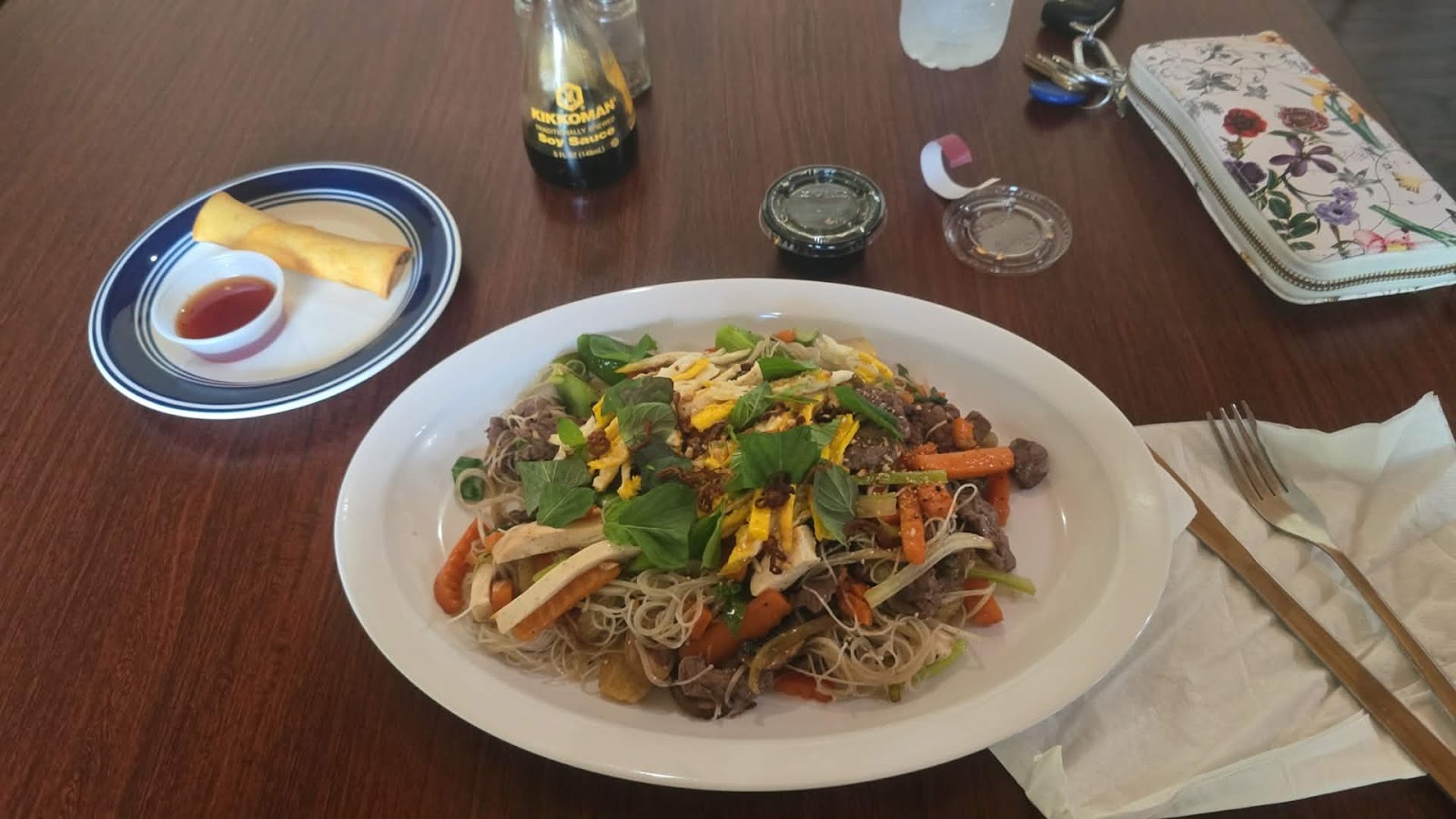Beef rice noodle plate with fresh herbs and egg roll